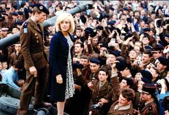 Sylvie Vartan debout sur un char saluant une foule d'appelés du contingent, 1964